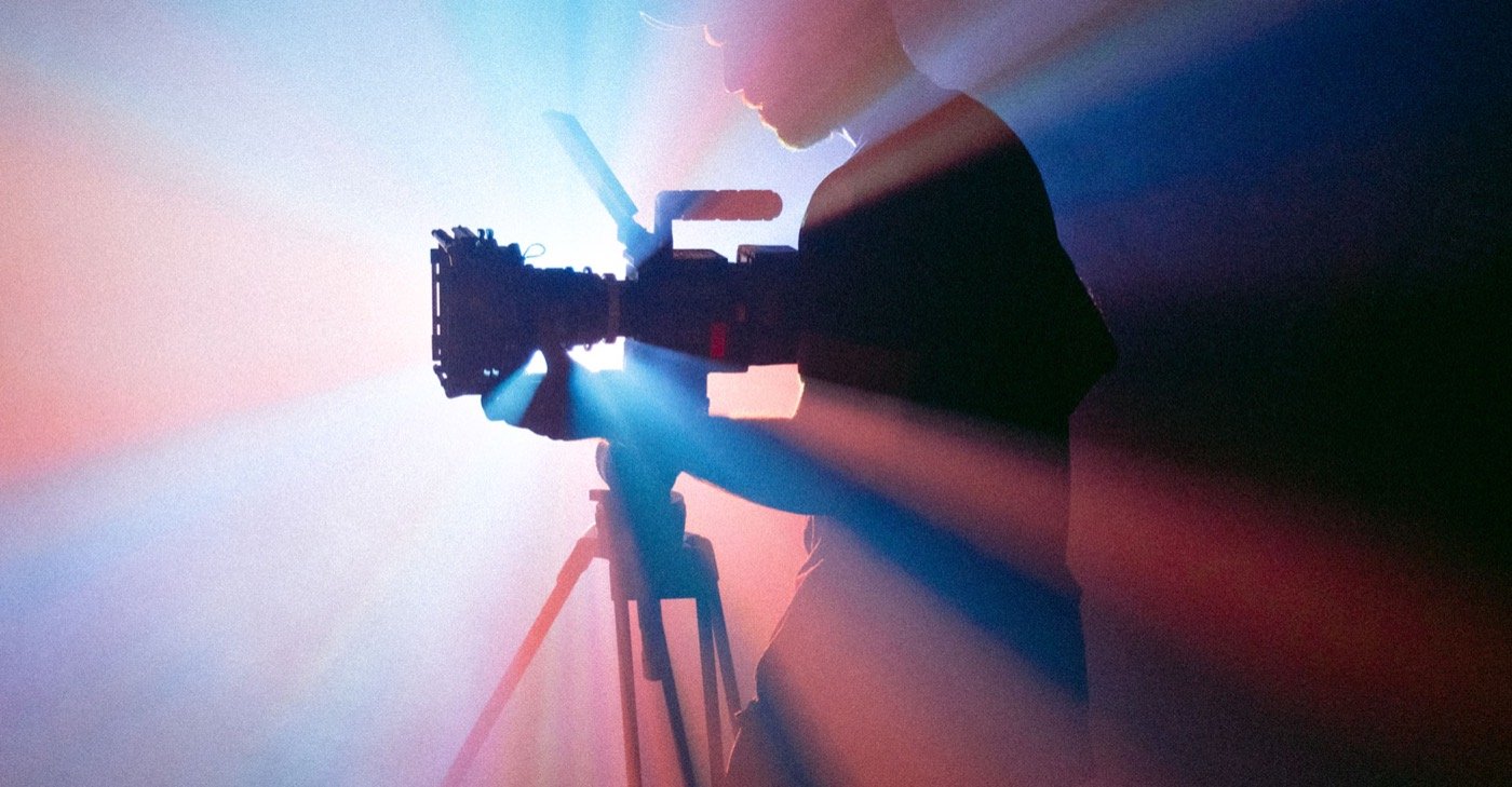 A camera silhouetted against stage lighting