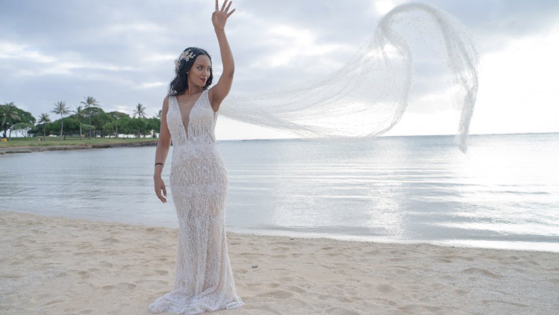 A bride on the shoreline with her veil caught in the wind